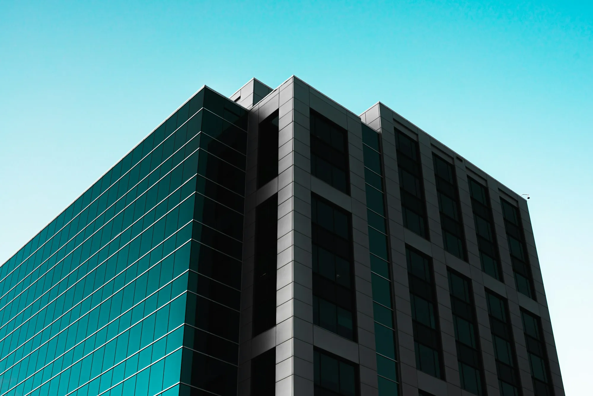 Dark glass office building against a clear blue sky