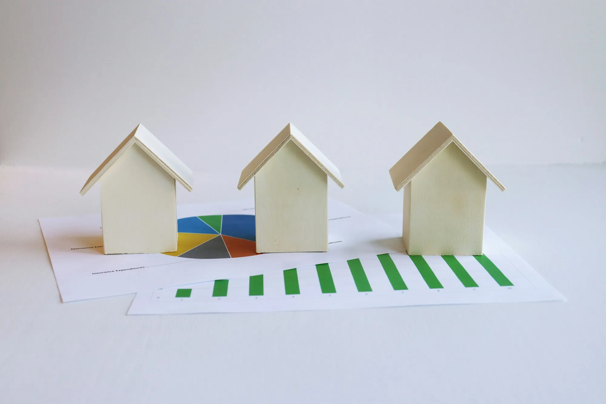 Three small model houses on top of financial charts