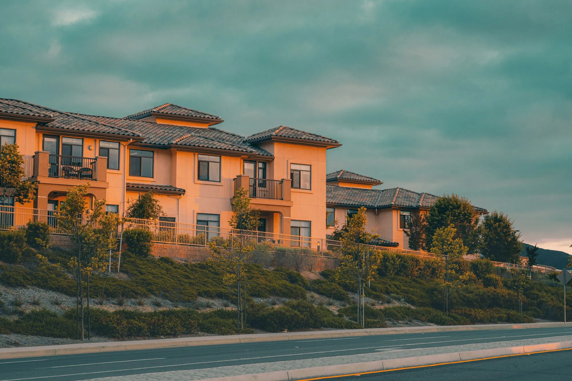 Row of stucco townhomes with tile roofs on a hillside